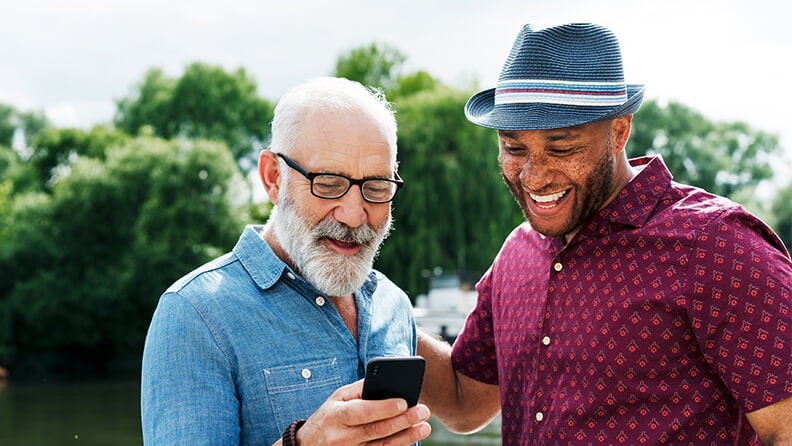 Two smiling men having a conversation outdoors