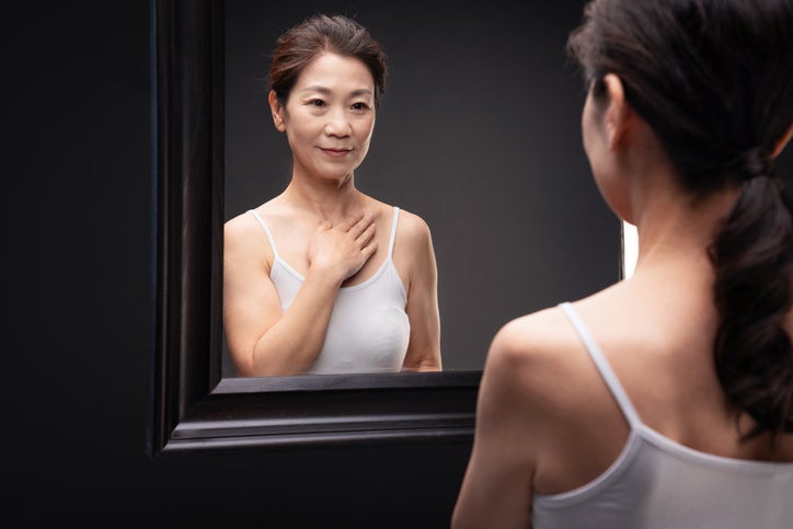 Midde-age woman examining herself in mirror
