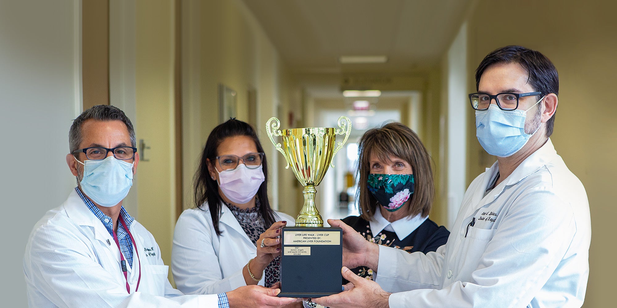 Doctors and patient hold trophy