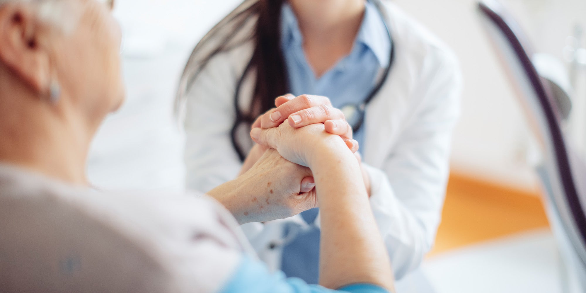 Doctor comforting patient by touching hands