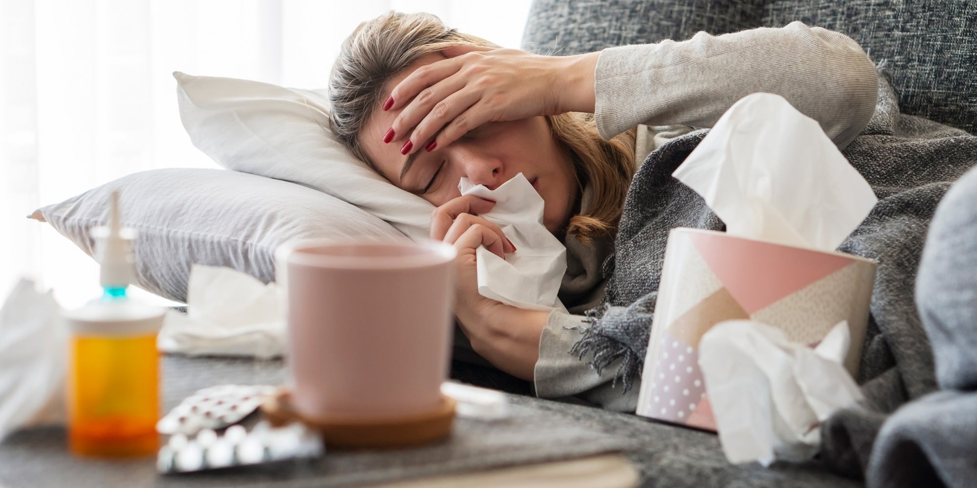 Woman holding her head with tissue in hand