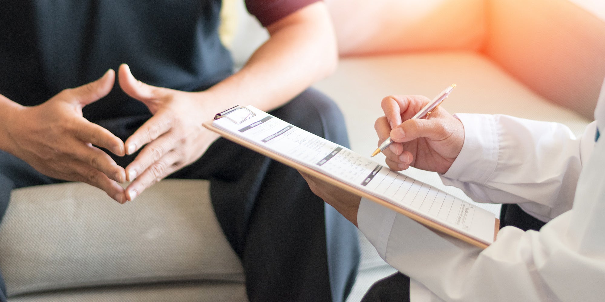 Man talking to doctor who is writing notes