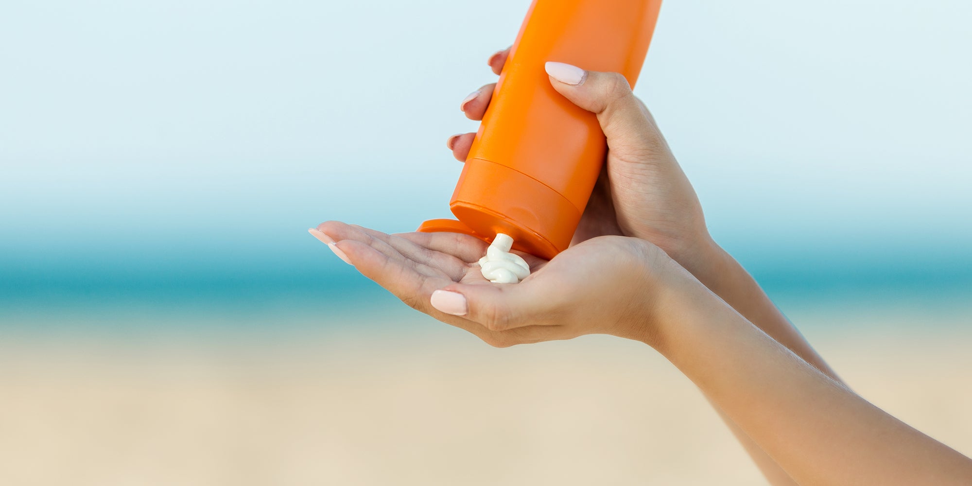 Person getting sunscreen out of bottle on beach
