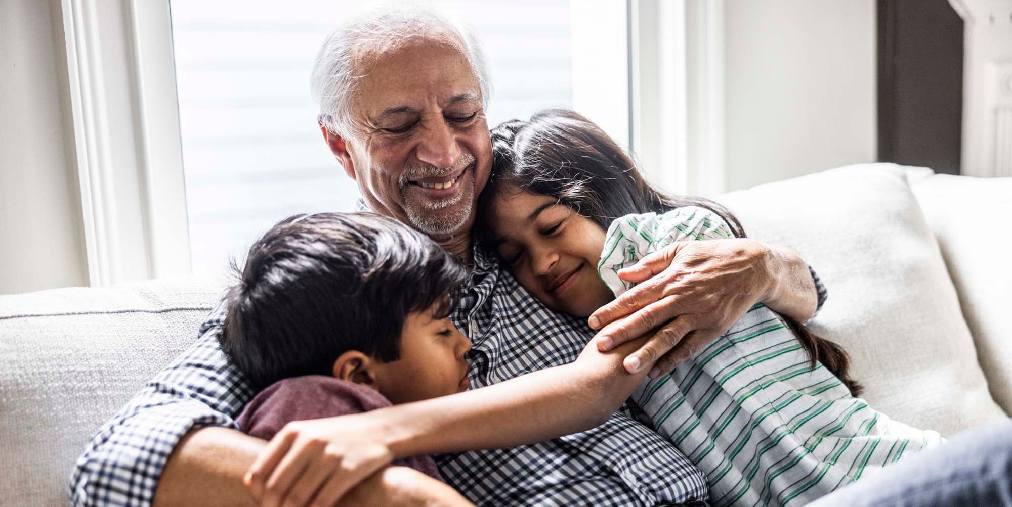 Grandfather hugging his grandkids on a couch