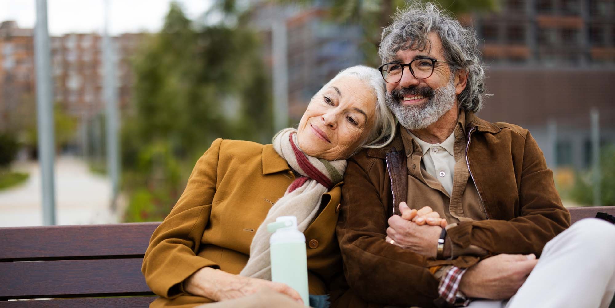 A couple embracing on a bench outside